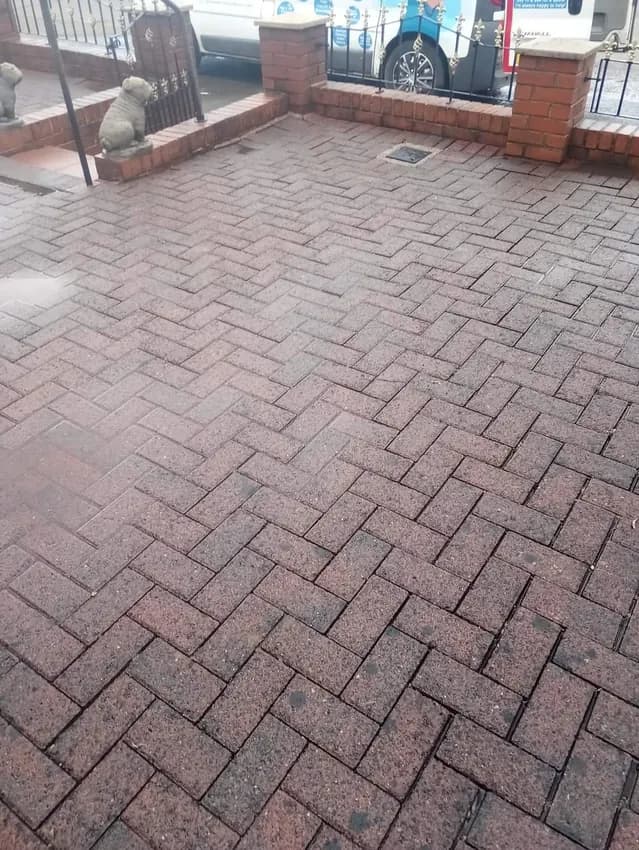 Red block paved patio after cleaning beside a brick house